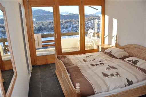 Schlafzimmer mit Doppelbett und Zugang zum unteren Balkon